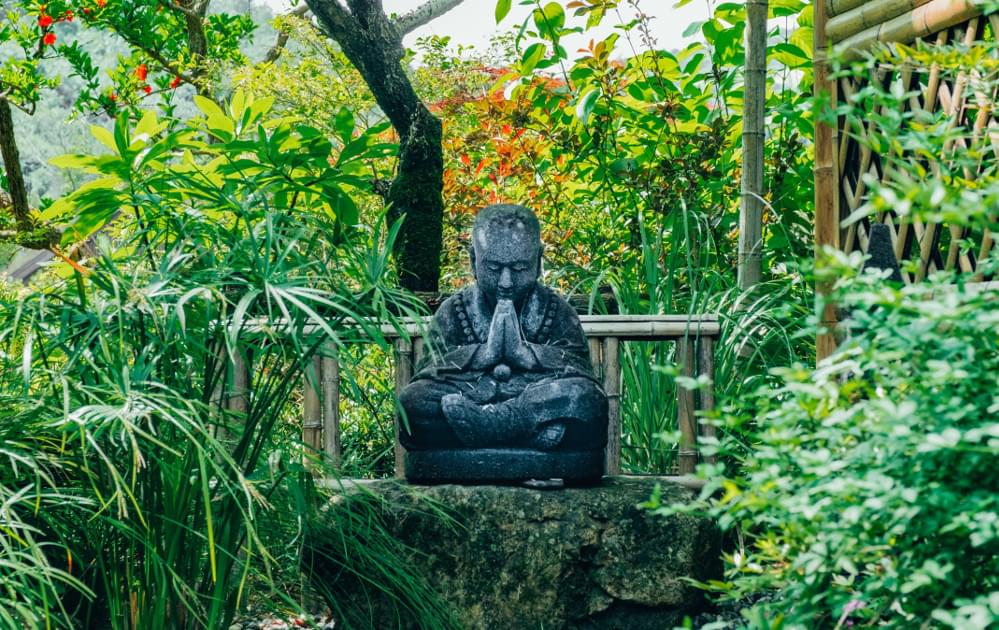 Buddha statue on a green rock in a garden