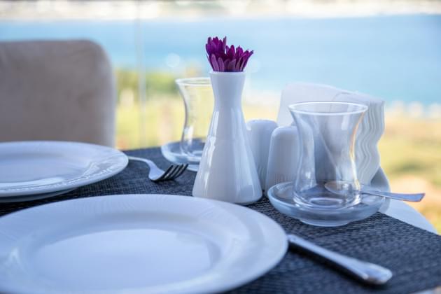 A table with two empty place settings on the shore of a river.