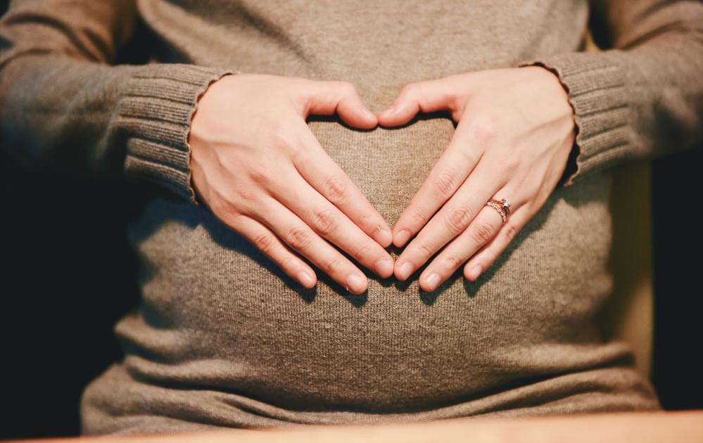 Heart hands over pregnant belly