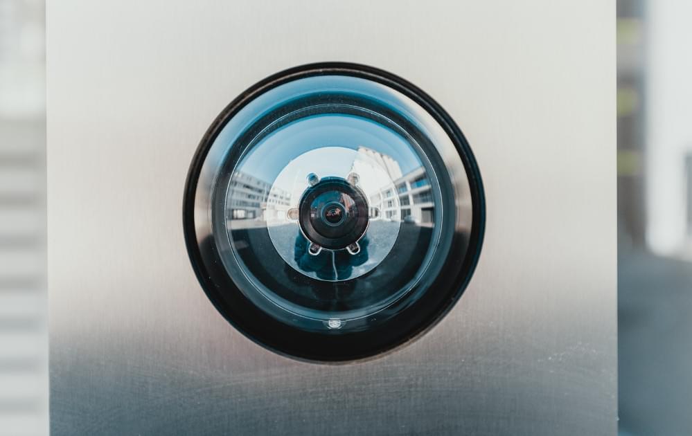 Security camera lens mounted on metal wall