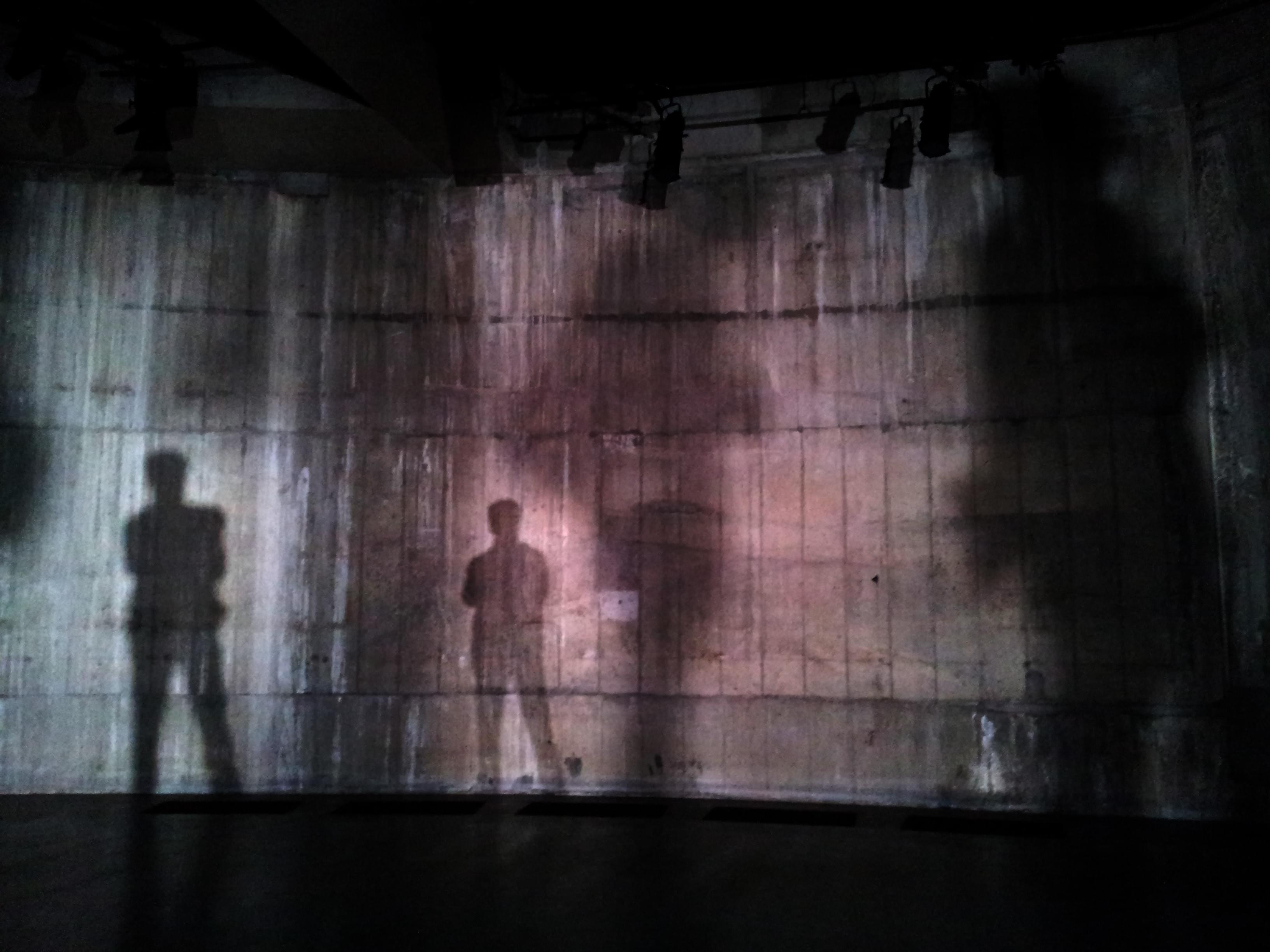 Silhouette of man standing near wall on dark area