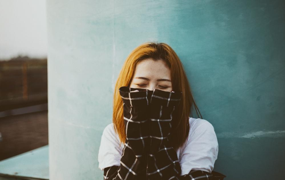 Woman leaning on wall covering her mouth