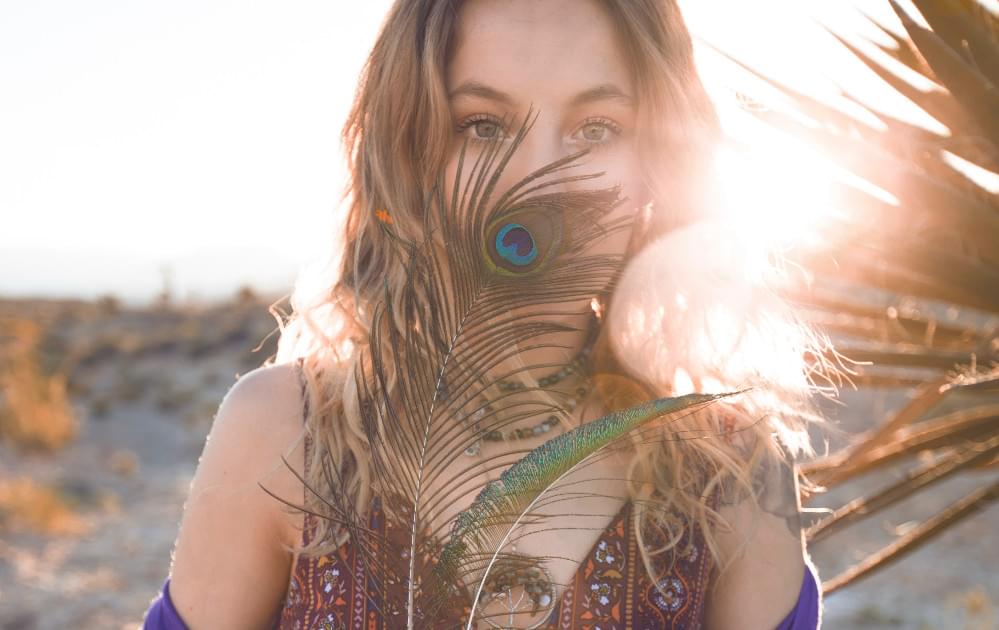 Woman obscuring face with feather