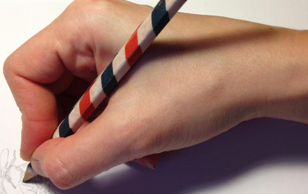 Hand writing with a red, white, and blue pencil